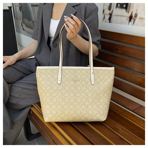 Detail of monogram tote bag with gold studs and slim handles in an outdoor setting