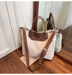 Close-up of canvas tote bag with brown leather handles and magnetic buckle closure