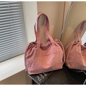 Detail of pink nylon tote bag with drawstring closure and large front pocket