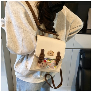 Detail of cream school-style backpack showing transparent pocket with colorful plush balls