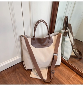Detailed macro view of cream canvas tote bag with brown leather trim and woven strap