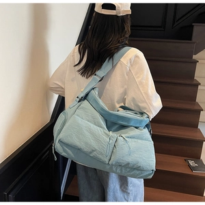 Detail of light blue nylon tote bag with dual zipper pockets and wide shoulder strap