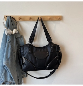 Détail du sac cabas noir clouté avec étoiles et fermetures éclair suspendu au mur