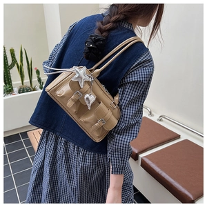 Details der hellen khakifarbenen Handtasche mit Krokoprägung und silbernen Anhängern