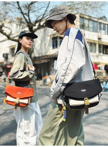 Outdoor nylon messenger bag detail with buckle closure and colorful doll charm accessory