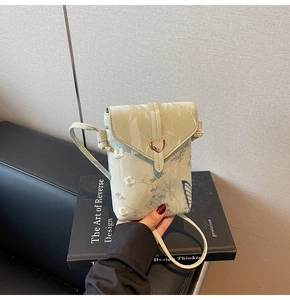 Détail du sac à téléphone en soie vert clair avec broderie florale et fermoir en cœur