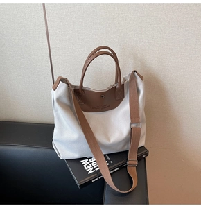 Detail of canvas tote bag showing the TAOCAIYU logo and premium brown leather handle straps