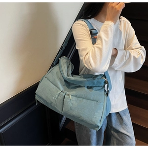 Detail of light blue nylon tote bag with double front zip pockets and wide strap