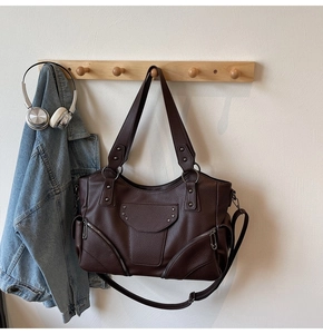 Détail du sac cabas marron avec rivets en étoile et fermetures éclair sur crochet en bois