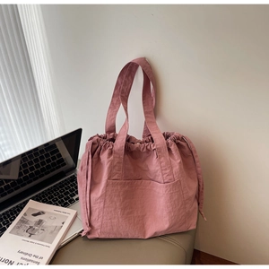 Close-up of pink nylon drawstring tote bag with large front pocket and long shoulder straps