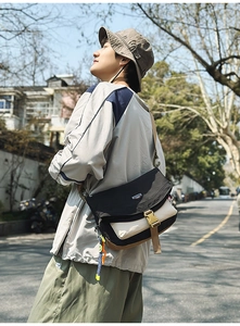 Close-up of contrast nylon messenger bag with buckle closure and woven charm detail