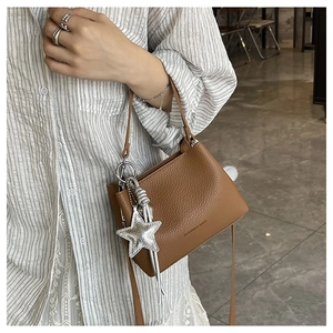 Detail of a brown lychee pattern bucket bag with star pendant and shoulder strap