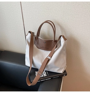 Detail of canvas tote bag showing stitching on brown leather strap and metal button closure