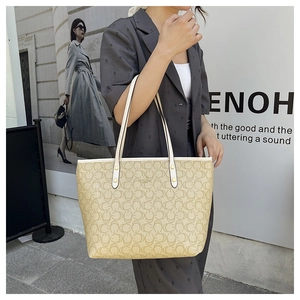 Street style view of woman wearing a large beige monogram tote bag on shoulder