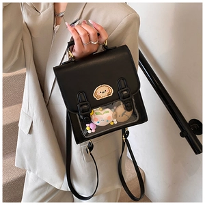 Detail of a black Ita bag with a transparent window featuring plush toys and embroidery