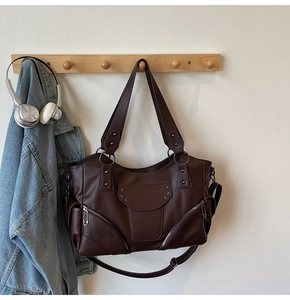 Détail du sac fourre-tout marron foncé avec rivets étoilés et fermetures éclair sur support