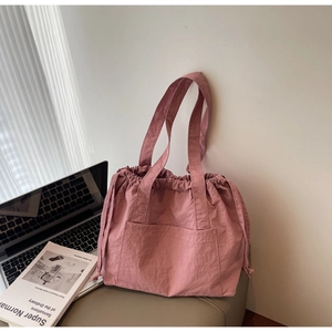 Detailed macro view of pink nylon drawstring tote bag with smooth lightweight texture