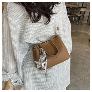 Close-up of brown textured leather bucket bag with silver star charm and printed logo