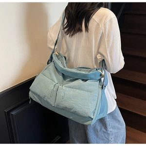 Close-up of mint green nylon tote bag featuring multi-pocket design and wide shoulder strap