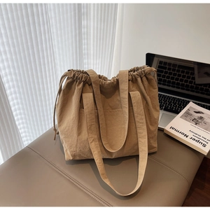 Macro detail of khaki nylon tote bag featuring drawstring closure and textured fabric