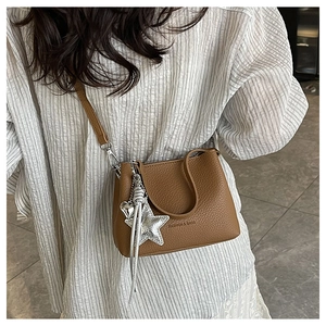 Close-up of brown litchi leather bucket bag with star and heart metal charms