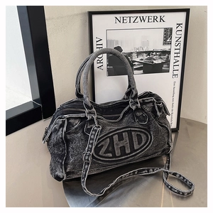 Dettaglio macro della borsa in denim nero lavato con ricamo ZHD e cerniera in metallo
