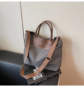 Detail of grey canvas tote bag with brown leather handles and adjustable shoulder strap