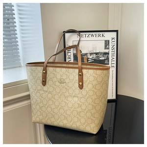 Detailed close-up of a large tote bag with monogram texture and premium brown handles