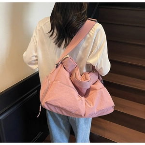 Rosafarbene Nylon-Umhängetasche mit breitem Gurt und mehreren Taschen in Lifestyle-Ansicht
