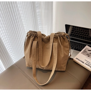 Detail shot of khaki nylon drawstring tote bag featuring a textured finish and side pockets
