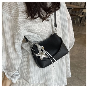 Detail of black leather bucket bag featuring silver star pendant and fringe tassel accents