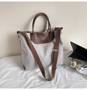 Detail of grey canvas tote bag with brown leather handles and adjustable shoulder strap