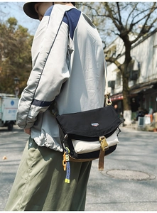 Detail of nylon messenger bag with yellow buckle and colorful woven rope charm
