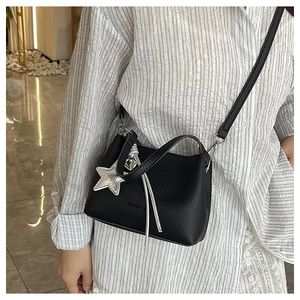 Detail of black mini crossbody bucket bag with silver star and heart charms for women