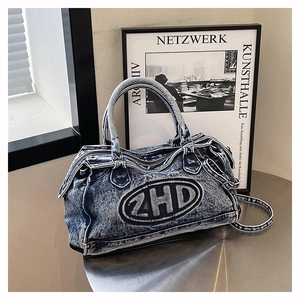Dettaglio della borsa in denim lavato con ricamo 2HD su un tavolo in metallo argentato
