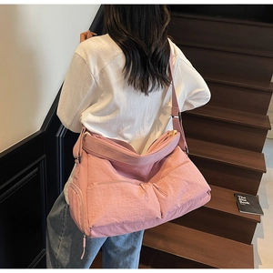 Detail der rosa Nylon-Umhängetasche mit Reißverschlussfächern und breitem Schultergurt
