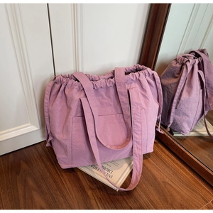 Detail of purple drawstring nylon tote bag with front pocket and textured fabric finish