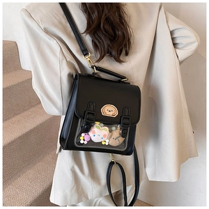 Detail of black ita bag featuring a clear PVC window with cute plush charms and embroidery
