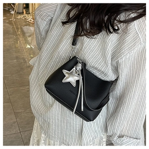Detail of black lychee grain leather bag with silver star charm and fringe tassels