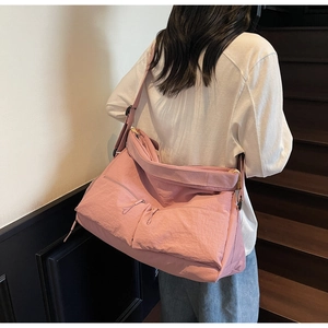 Rear view of a model wearing a large pink crossbody nylon bag on a modern staircase
