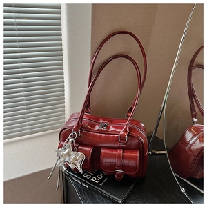Detail der weinroten Retro-Handtasche mit Doppeltaschen, Krokostruktur und Sternanhänger