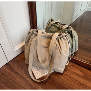Detail of nylon drawstring tote bag showing textured fabric and spacious side pockets