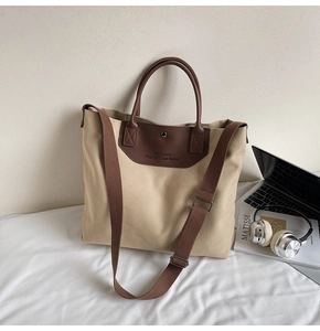 Detail view of khaki canvas tote bag with leather handles and laptop accessory