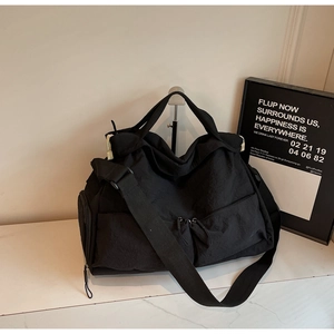 Detail of black waterproof nylon tote with multiple zipper pockets and adjustable strap