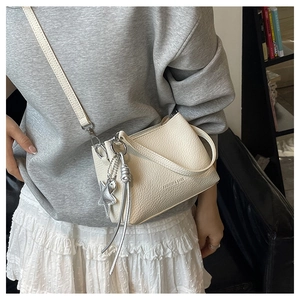 Detail of off-white lychee leather crossbody bag with star pendant and fringe charm