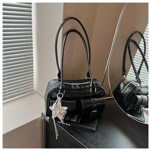 Details der glänzenden schwarzen Ledertasche mit Krokoprägung und Sternanhänger