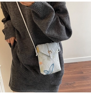 Détail du sac de téléphone en toile brodée avec motifs floraux et boucle en forme de cœur