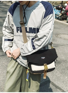 Close-up of black and white nylon messenger bag featuring buckle closure and charm