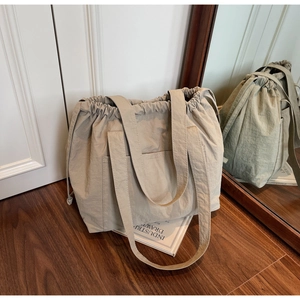 Macro detail of khaki drawstring nylon tote bag with pleated texture and front pocket