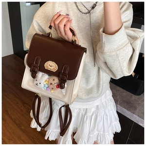 Detail view of British style two-tone leather ita bag with clear window and plush charms